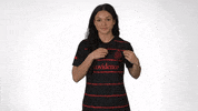 Video gif. Sophia Smith, a soccer player for the Providence FC team, wears a jersey and smiles at us, shaking the team's logo on her shirt then holding up a number 1. 