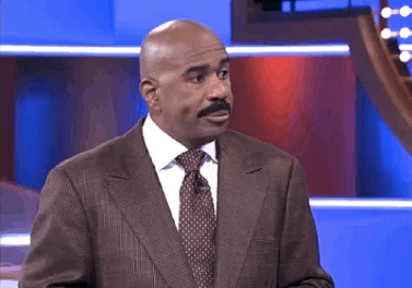 Reality TV gif. Steve Harvey on Family Feud. He looks at someone and smiles with closed lips and nods slightly before turning away and widening his eyes with frustration.