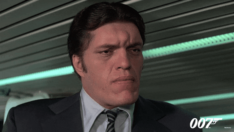 Movie gif. Richard Kiel as Jaws in Moonraker smiles down at someone, revealing a mouth full of metal teeth.
