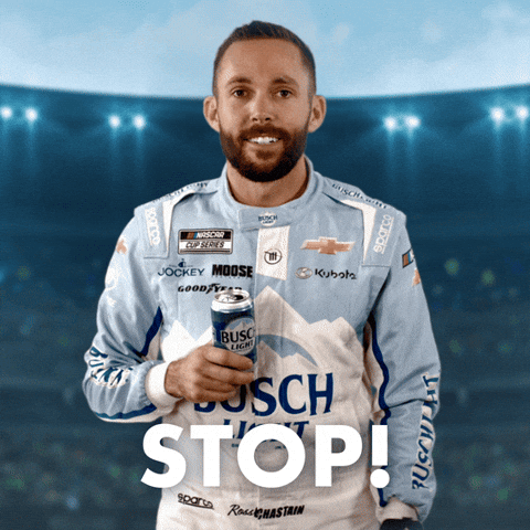 Sponsored gif. NASCAR driver Ross Chastain motions to stop with his left hand while holding a can of Busch Light beer in his right hand. He wears a driver fire suit decorated with many sponsor logos with the largest being the Busch Light beer logo across the center of his abdomen. Text reads, “Stop!”