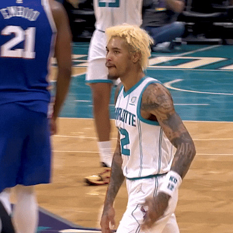 Sports gif. Charlotte Hornet player Kelly Oubre walks across the court and looks out at the audience. He kisses his hand and lifts his hand up in the air, and does the same with his other hand.