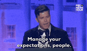 Video gif. Saturday Night Live's Colin Jost stands at a podium at the 2024 White House Correspondents' Dinner and delivers a joke. He says, "Manage your expectations people."