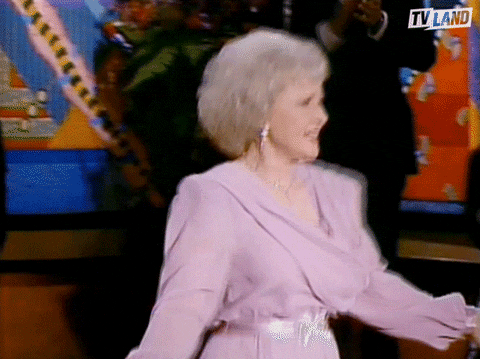 TV gif. Betty White as Rose on Golden Girls dances around, shimmying her chest confidently, as people clap on the sidelines of the dance floor.