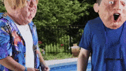 Video gif. Two guys wearing oversized, creepy paper mache heads give each other a double thumbs up, bending and shaking as they cheer for each other.