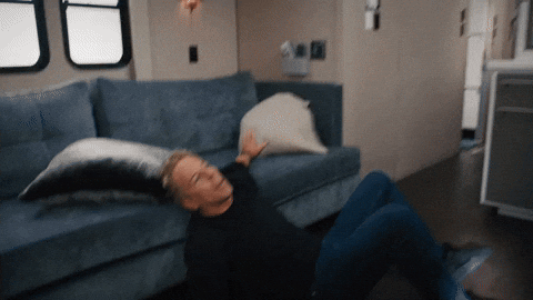 Reality TV gif. A man tries to steady himself against a couch while seated on the floor. Text, "Oh my."