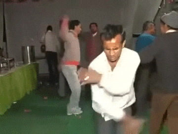 Video gif. A group of men dance with restraint as a man in front attempts to break dance.