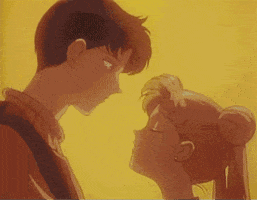Anime gif. Mamoru bends down to share a tender kiss with Usagi against an intimate, hazy yellow backdrop.