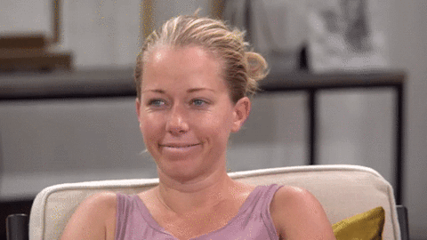 Reality TV gif. Kendra Wilkinson in Marriage Boot Camp. She's sitting in a chair and has a smirk on her face. She rolls her eyes while smiling and puts her hand up to her chin to lean on it.