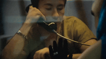 Music video gif from Sabrina Carpenter's music video for "Please Please Please." She visits Barry Keoghan in jail. They touch hands through the glass partition.