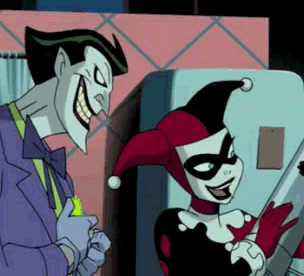 Cartoon gif. The Joker kisses Harley Quinn on the cheek. She smiles and stares adoringly at him while he flashes us a large, toothy smile.