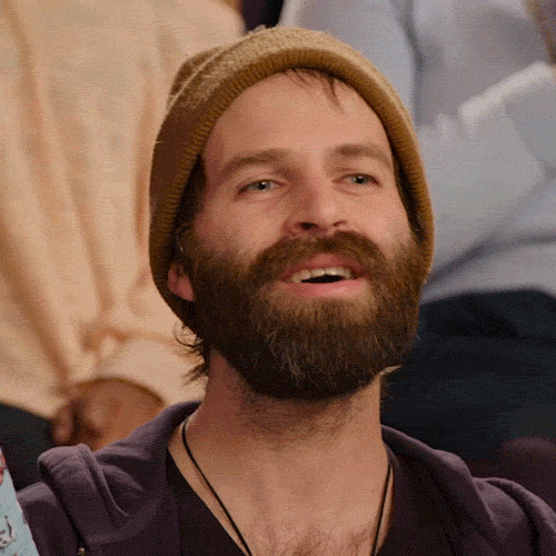 Video gif. Man with a beard and beanie laughs and then leans his head back, squinting his eyes and losing his smile as if confused by what he just heard.