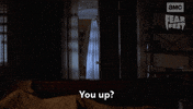 Sponsored gif. Person dressed like a ghost under a white bed sheet slowly pushes open a bedroom door and asks, “You up?”