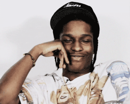 Celebrity gif. ASAP Rocky smiles as he tilts his head forward and covers his eyes with a hand.