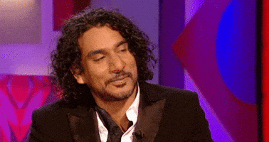 Celebrity gif. Naveen Andrews is leaning back and considers a question before opening his mouth to speak.
