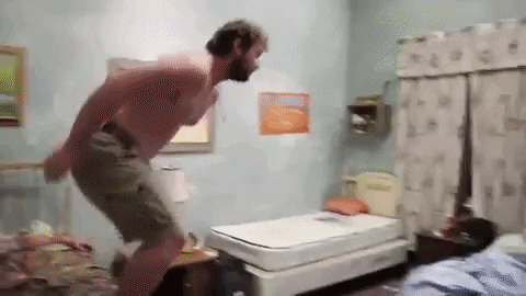 Reality TV gif. A shirtless man with a beard from Party Down South leaps onto a bed.