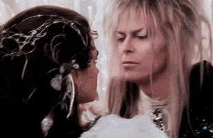 Movie gif. Jennifer Connelly as Sara and David Bowie as Jareth dressed in formal attire slow dance in circles at a surrealistic ball. 