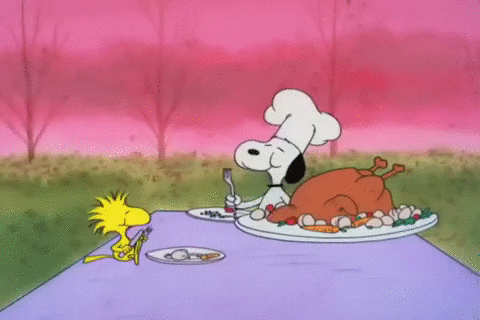 Peanuts gif. Snoopy wears a chef's hat and carves a large turkey and takes a bite, standing at a table outside with Woodstock.