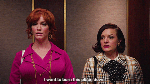 TV gif. Christina Hendricks as Joan in Mad Men. She's in the elevator with Peggy and she looks calmly furious. She declares, "I want to burn this place down," while Peggy takes a deep breath and looks at her with understanding.