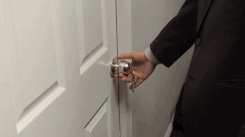 Video gif. Closeup on a man's hand wearing a suit and turning the doorknob to an office as he opens the door and walks in.