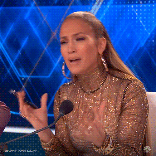 Reality TV gif. Jennifer Lopez as a judge in World of Dance scrunches her forehead and raises her hands to shrug like she's bewildered to the point of being annoyed about it.