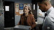 TV gif. In a locker room, Melissa Roxburgh as Michaela is holding a stack of white boxes goes to leave and is roughly stopped by a man, who grabs her arm and starts to say something to her.