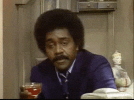 TV gif. Demond Wilson, sitting down with a drink, laughs hard and points at us.