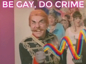 Digital art gif. Grinning villain holds a device with an animated rainbow wave emanating from it, from which Batman and Robin shield themselves. Next, Robin sternly approaches Batman, who is now wearing a pink cowl. Text, "Be gay, do crime."