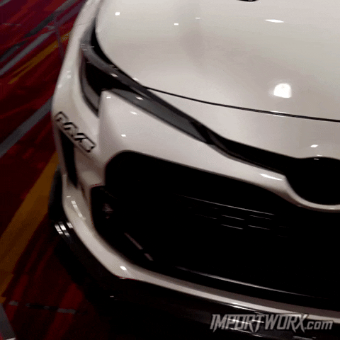 Video gif. We scan over the front of a glossy white Toyota Corolla. 