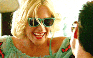 Movie gif. Christian Slater as Clarence Worley and Patricia Arquette as Alabama Whitman both wear sunglasses. They smile and nod at each other, and then move closer to each other to kiss.