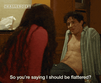 Movie gif from "Challengers." Tashi Donaldson and Patrick Zweig sit on the floor, his shirt is unbuttoned. Caption reads, "So you're saying I should be flattered?"