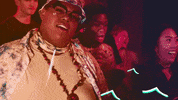 Music video gif. A man in a Louis the Child video dances near others as animated white swirls cover his eyes. 