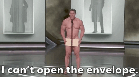 Oscars 2024 GIF. A naked John Cena has finally made it to the microphone with the Oscars envelope covering his privates. He looks frightened as he has a sudden realization that the winner is in the envelope. The envelope that holds his dignity together. He finally admits to us, "I can't open the envelope."