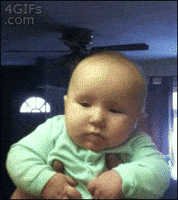 Video gif. Man holding a baby under the arms gives the baby a big cheek kiss, and then the baby sticks out his lower lip, appearing sad.