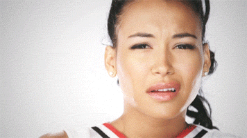 Celebrity gif. Naya Rivera dressed as cheerleader Santana Lopez from Glee gives us a judgmental stank face and shakes her head.
