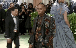 Met Gala 2024 gif. Lena Waithe poses for the cameras wearing a leather suit with floral embroidery.