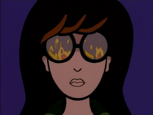 Cartoon gif. Daria stares at us with a grim, serious face. Her glasses reflect flames.