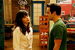 TV gif. Zooey Deschanel as Jessica and Jake Johnson as Nick in New Girl. She turns to walk away as he grabs her arm and pulls her into a passionate kiss. 
