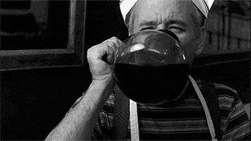TV gif. A black-and-white scene of Bill Murray wearing a paper hat and apron, drinking straight out of a coffee pot.