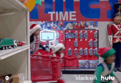 TV gif. Wearing Christmas outfits, Yara Shahidi as Zoey, Marsai Martin as Diane, Miles Brown as Jack, and Marcus Scribner as Andre on Black-ish run down a toy aisle at a department store with Santa, throwing every toy they can see into the cart in a frenzy.
