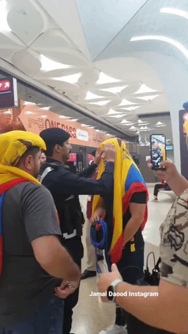 Qatari Policeman Adjusts Ecuadorian Fan's Headscarf in Doha
