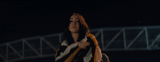 Music video gif. Noah Cyrus does a hand-across-the-throat motion, as if she were saying to cut it. 