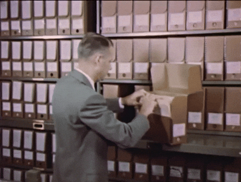 A man organizing files in a large archive, symbolizing AQuA document classification and distribution.