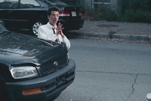 Movie gif. Jay Baruchel as Kirk Ketnner in She's Out of My League walks on his knees around a dark green Toyota Rav4 carrying a satchel with hands clasped like he's down on his knees pleading or begging for something.