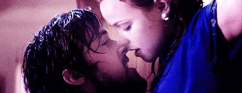 Movie gif. Ryan Gosling as Noah and Rachel McAdams as Allie in The Notebook. They're drenched from being in the rain and Allie is pressed up against the wall of a home. Her hands are behind her head as Noah leans up and deeply kisses her.