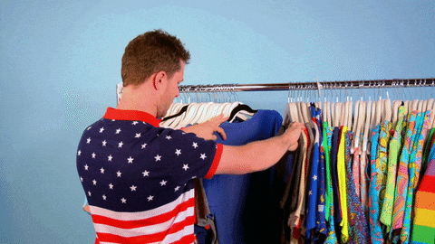estou procurando em espanhol

DESCRIÇÃO DA IMAGEM: Um homem com uma camiseta com a bandeira dos EUA está olhando uma arara cheia de camisetas coloridas. 