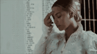 Video gif. A woman with her eyes closed in prayer crosses herself.
