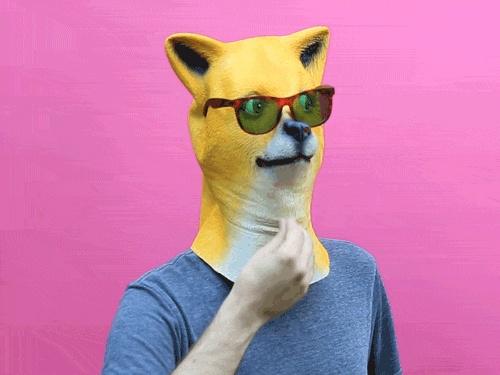 Video gif. Person wears a mask that looks like a Shibu Inu. The mask is looking to its side and wears sunglasses. The person strokes under the mask’s chin like they’re thinking hard.