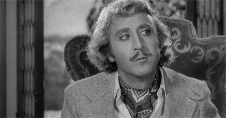 Movie gif. Gene Wilder in Young Frankenstein sits and faces us, looking around with his eyes as he thinks, raising his eyebrows slightly and tilting his head as he begins chewing again. 