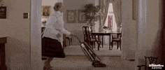 Movie gif. Robin Williams as Mrs Doubtfire dances while vacuuming a room.