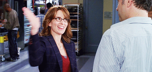 TV gif. Tina Fey as Liz Lemon from 30 Rock sticks out her tongue and gives a high five to her coworker Pete Hornberger, played by Scott Adsit.